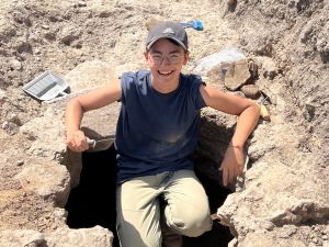 Young man sitting in a hole in an archaeological trench