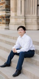 Asian young man sitting on the steps of a Gothic cathedral